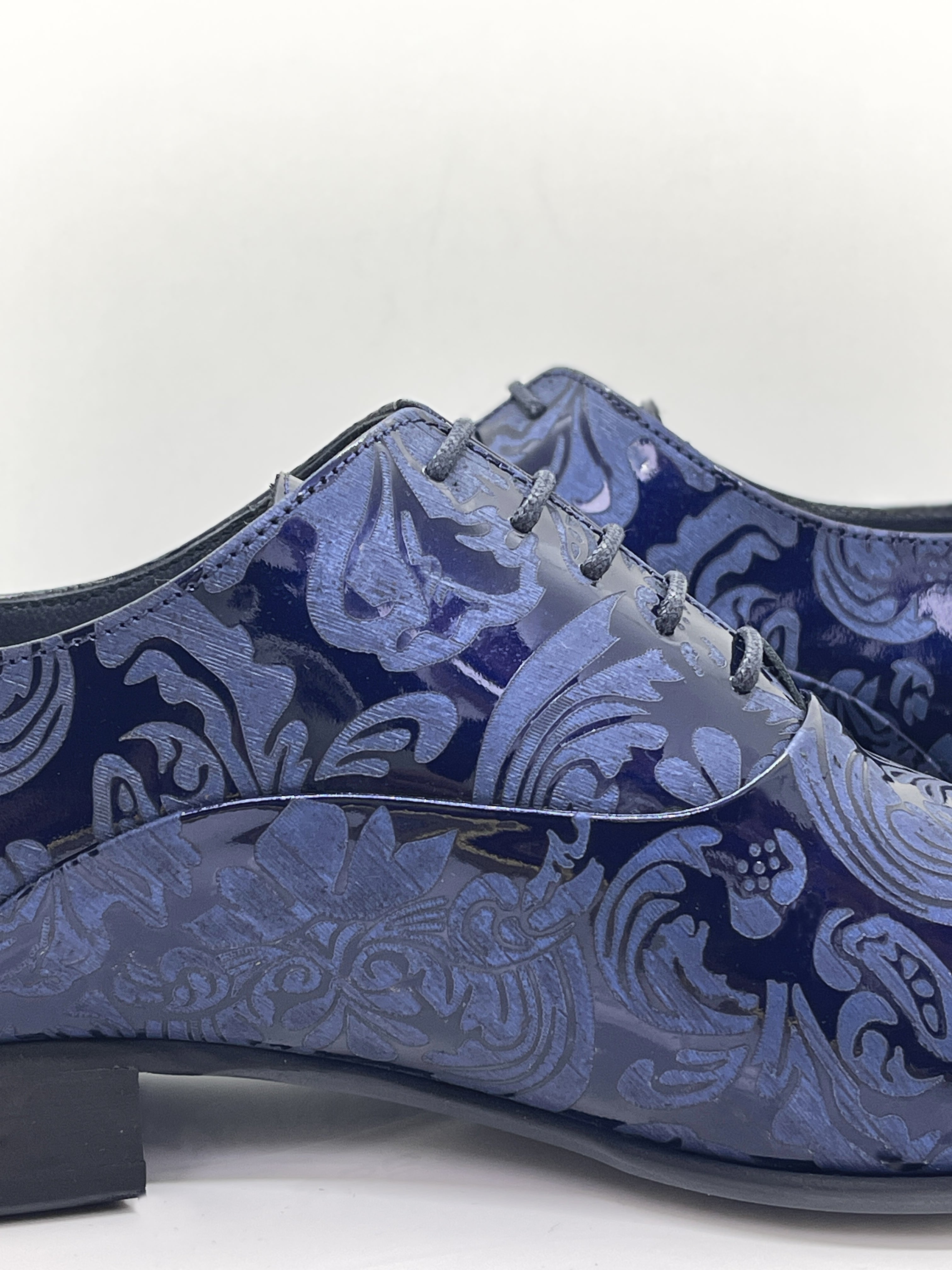 Handgefertigter Herrenschuh aus echtem Leder mit einer filigranen Lasergravur in Form von Paisley-Ornamenten und eleganten Lackdetails in Blau.